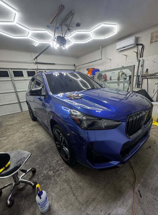 Blue BMW X1 in shop with tint